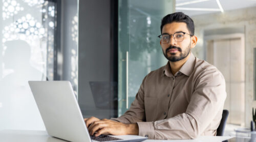 Confident Indian businessman working on laptop in office Confident Indian businessman working on laptop in office