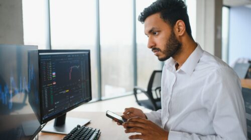 Portrait of a positive successful Indian or Arabian trader, stock market broker, Crypto charts on laptop screen Portrait of a positive successful Indian or Arabian trader, stock market broker, Crypto charts on laptop screen