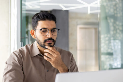 Serious Indian businessman thinking at office desk Serious Indian businessman thinking at office desk