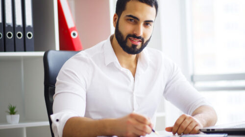 Young handsome entrepreneur sitting at desk and using laptop in office. Young handsome entrepreneur sitting at desk and using laptop in office.