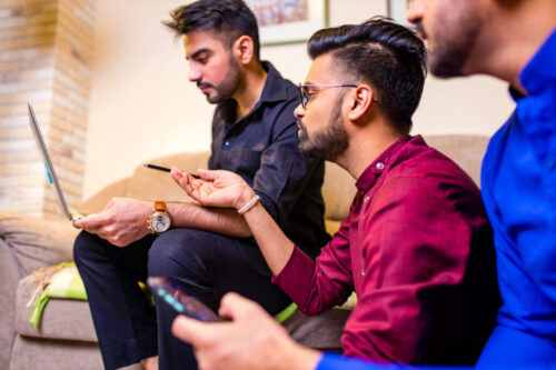 friends from india looking something interesting on laptop in livingroom friends from india looking something interesting on laptop in livingroom